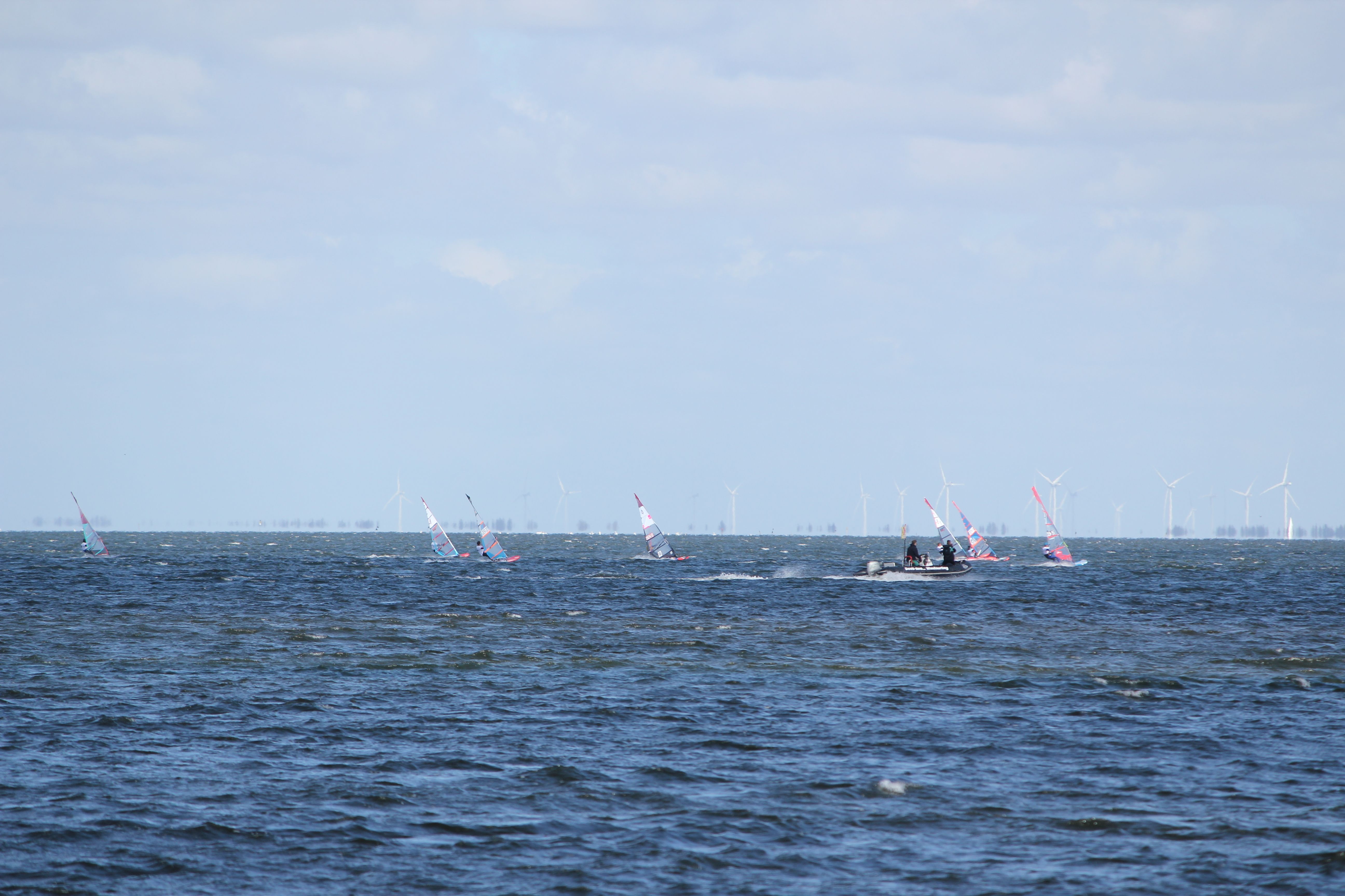 Two surfers riding together on a tandem windsurf board, enjoying the waves